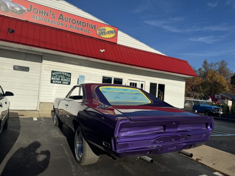 Vintage muscle car in purple color parked in front of John's Automotive shop.