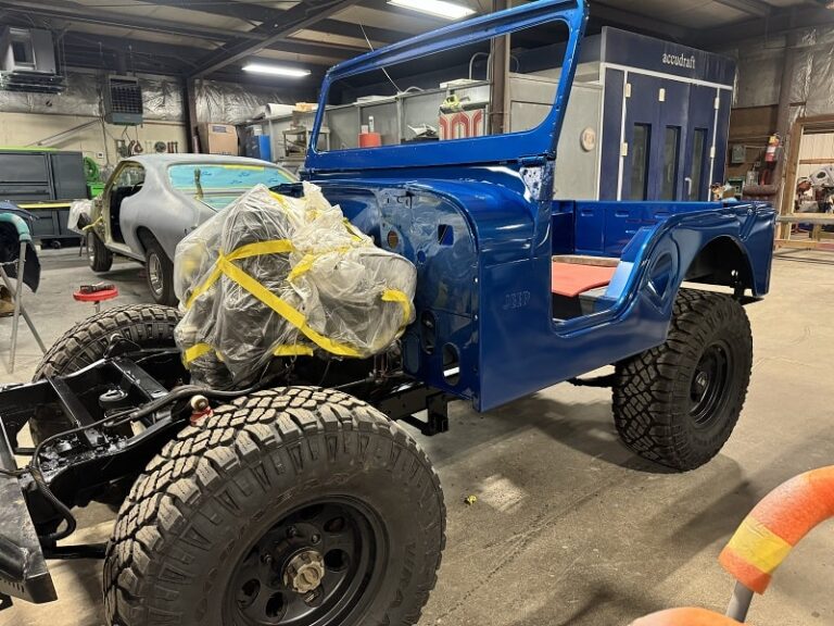 Vintage Jeep being restored with a fresh blue paint job and new tires.