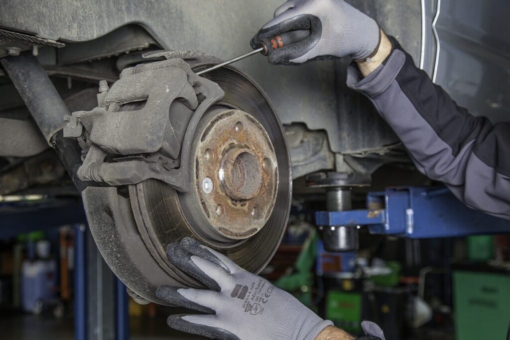 Technician replacing brake pads on a car's disc brake system.