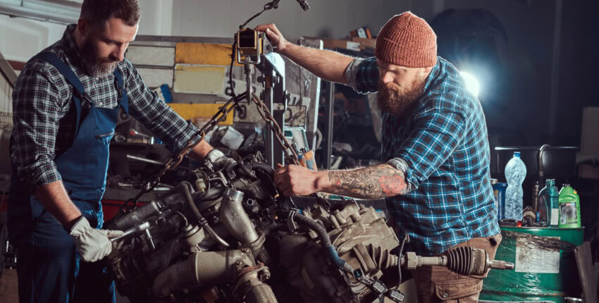 Mechanics rebuilding an engine in a workshop setting.