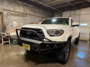 White Toyota truck with off-road bumper in garage.