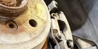 Close-up of brake caliper and rotor in auto repair shop.