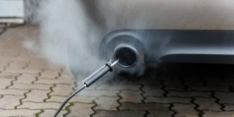 Car exhaust pipe emitting smoke during emission testing at Kabayan Auto Repair.