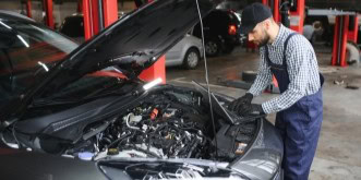 Mechanic inspecting car engine at Kabayan Auto Repair LTD workshop.