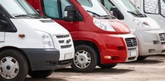 Lineup of commercial vans at Kabayan Auto Repair LTD for maintenance and service.