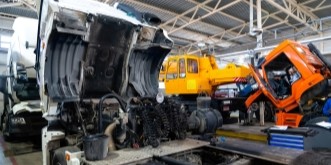 Damaged trucks and construction equipment at Kabayan Auto Repair LTD workshop.