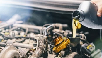 Mechanic pouring engine oil into a car engine during maintenance.