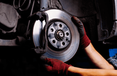 Technician inspecting a vehicle's brake disc during brake service.