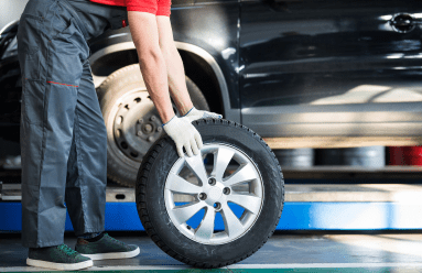 Technician changing a car tire at Kerrigan's Automotive shop.