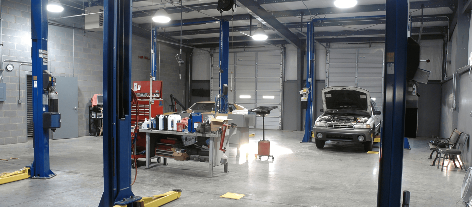 Auto repair shop interior with vehicles, tools, and equipment for vehicle maintenance and repairs.