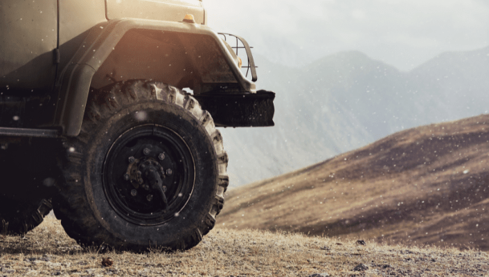 Off-road vehicle with large tires on rough terrain, showcasing vehicle repair and maintenance servic.