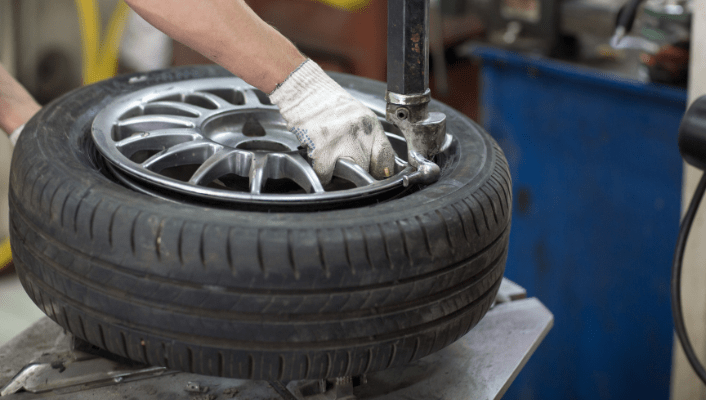 Technician performing tire and wheel alignment on a vehicle.