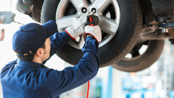 Technician performing wheel alignment on a vehicle in the auto repair shop.