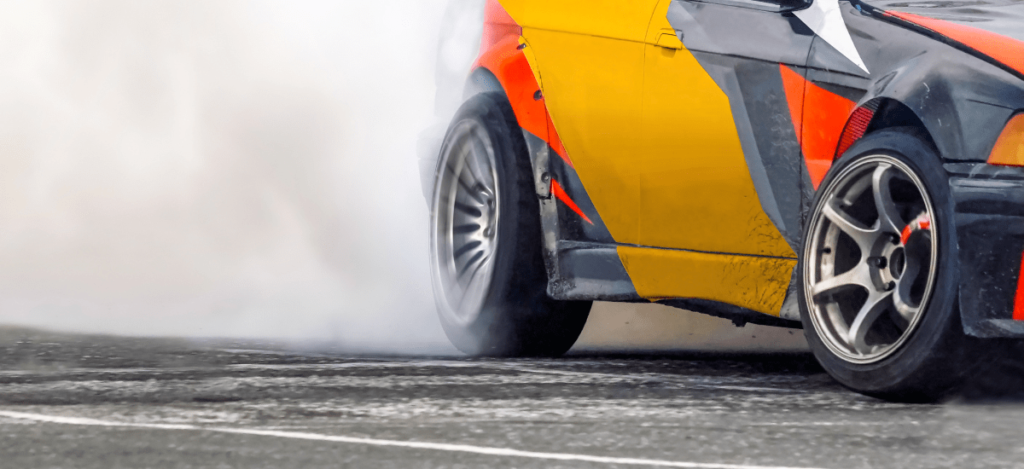 Sportscar performing a tire burnout on the track, showcasing tire grip and performance.