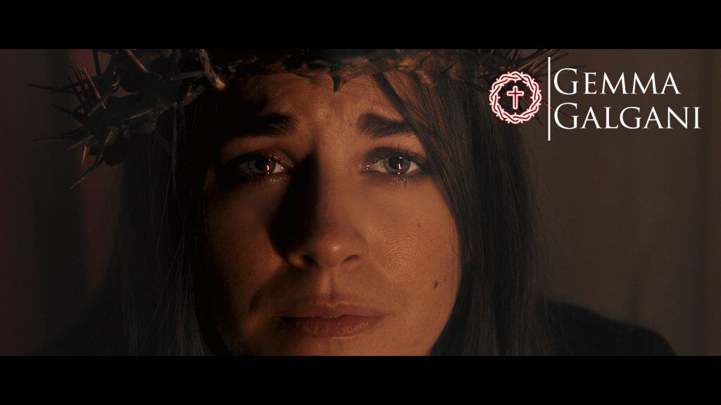 Rostro de una mujer con expresión emotiva, simbolizando fe y esperanza, con corona de espinas y una cruz en el fondo, en un entorno espiritual y religioso.