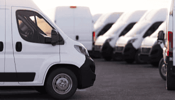 Fleet of white service vans parked at Legacy Tire & Auto Repair facility.