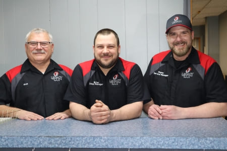 Friendly auto repair team at Legacy Tire & Auto Repair in a service center.