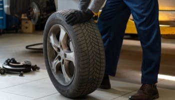 Technician changing a car tire in auto repair shop.