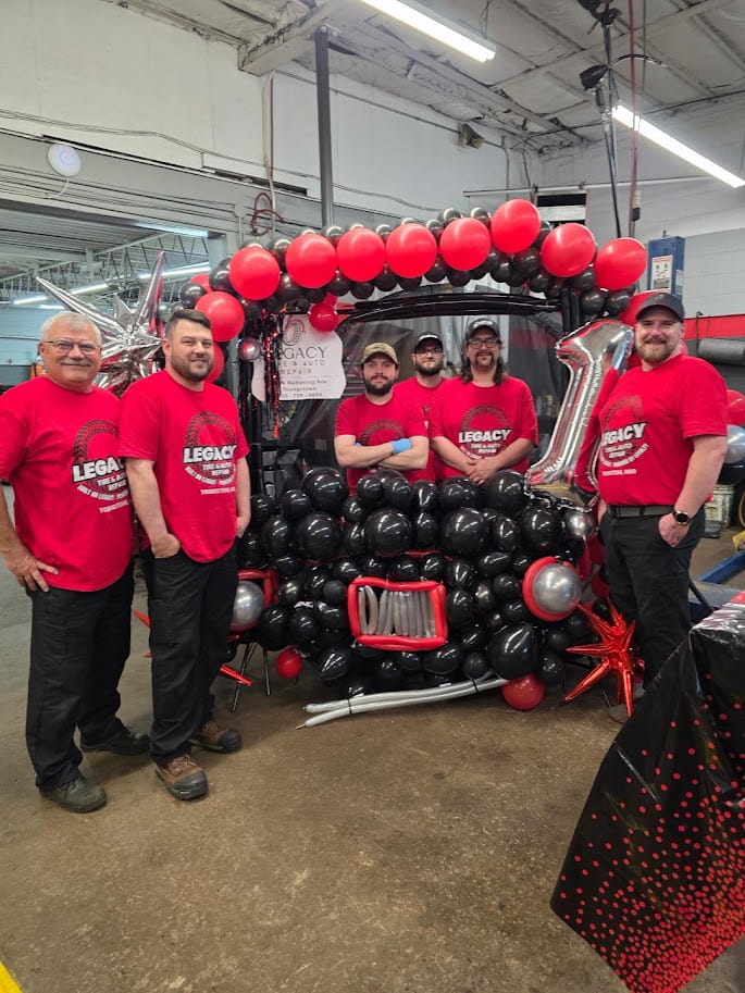 Balloon arch decoration featuring red, black, and silver balloons at Legacy Tire & Auto Repair event.