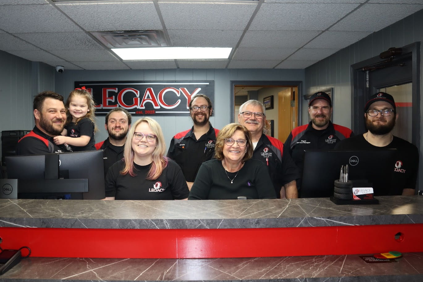 Friendly team at Legacy Tire & Auto Repair reception desk in a professional auto service shop.