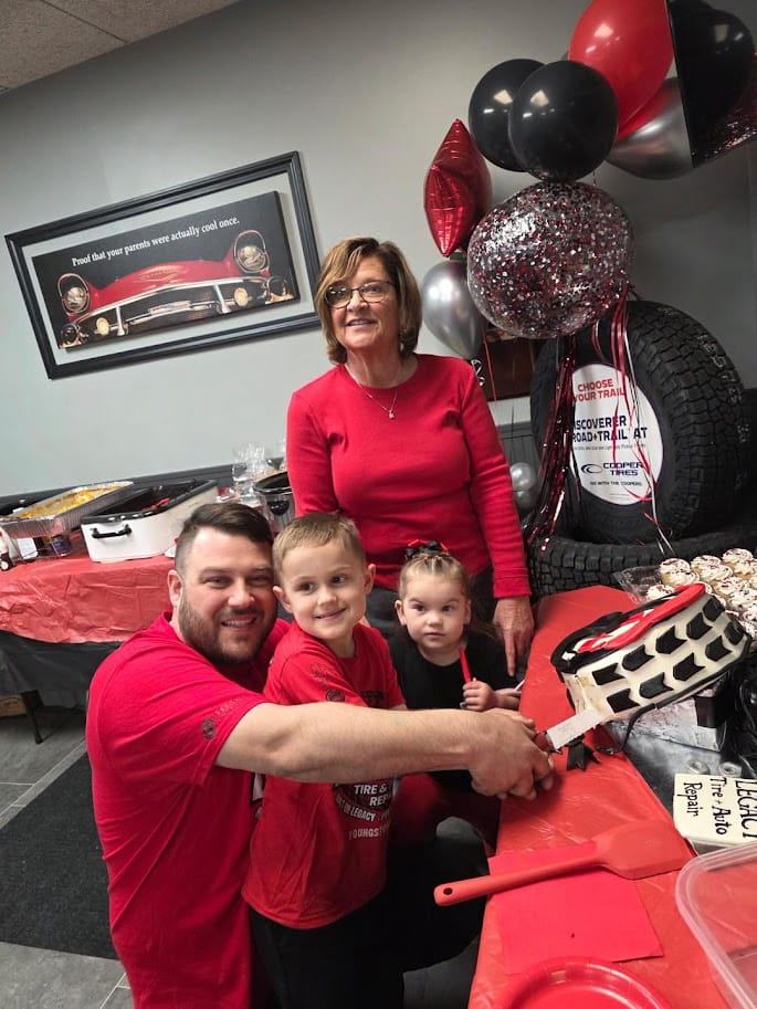 Family celebrating at Legacy Tire & Auto Repair with balloons and cake.