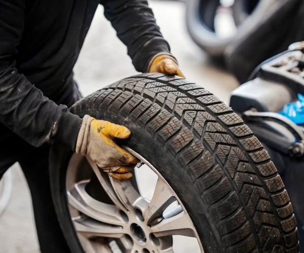 Technician changing a car tire at Legacy Tire & Auto Repair.