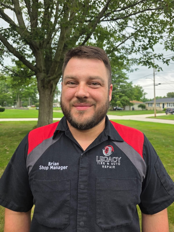 Shop manager Brian at Legacy Tire & Auto Repair smiling outdoors.