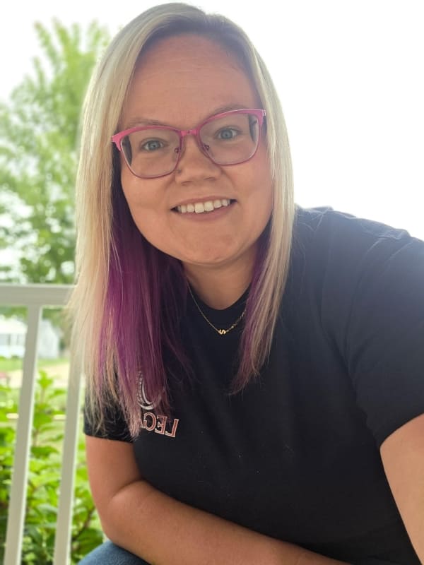 Smiling woman with glasses at Legacy Tire & Auto Repair.