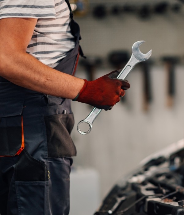 Auto repair technician holding a wrench in a garage setting.