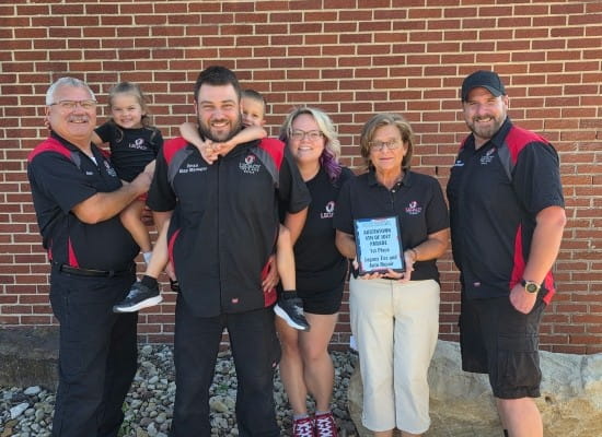 Group photo of Legacy Tire & Auto Repair staff and customers outside.