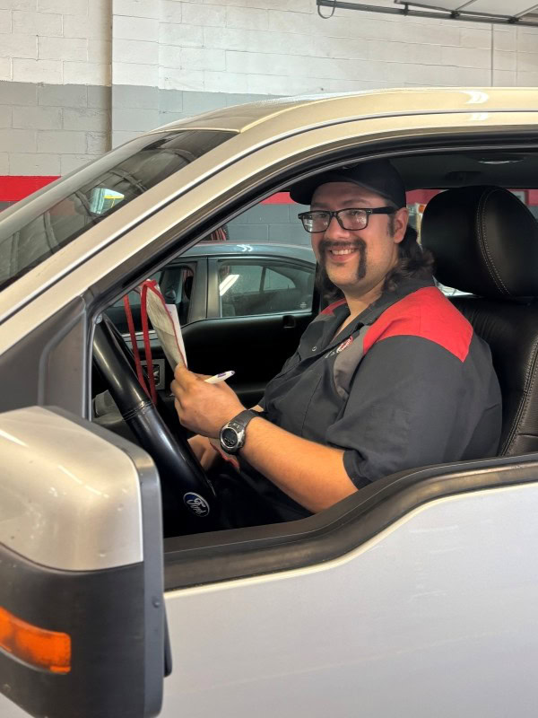 Smiling man in a vehicle at Legacy Tire & Auto Repair.
