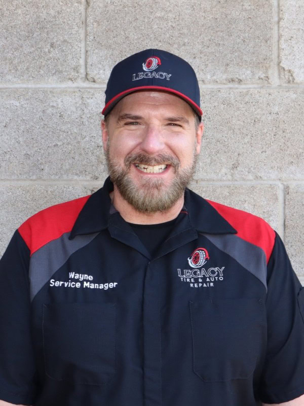 Service manager at Legacy Tire & Auto Repair smiling in uniform.