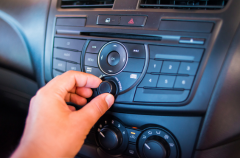 Close-up of a hand adjusting the car's A/C and heating controls.
