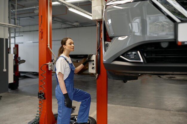 Auto repair technician inspecting vehicle under lift.