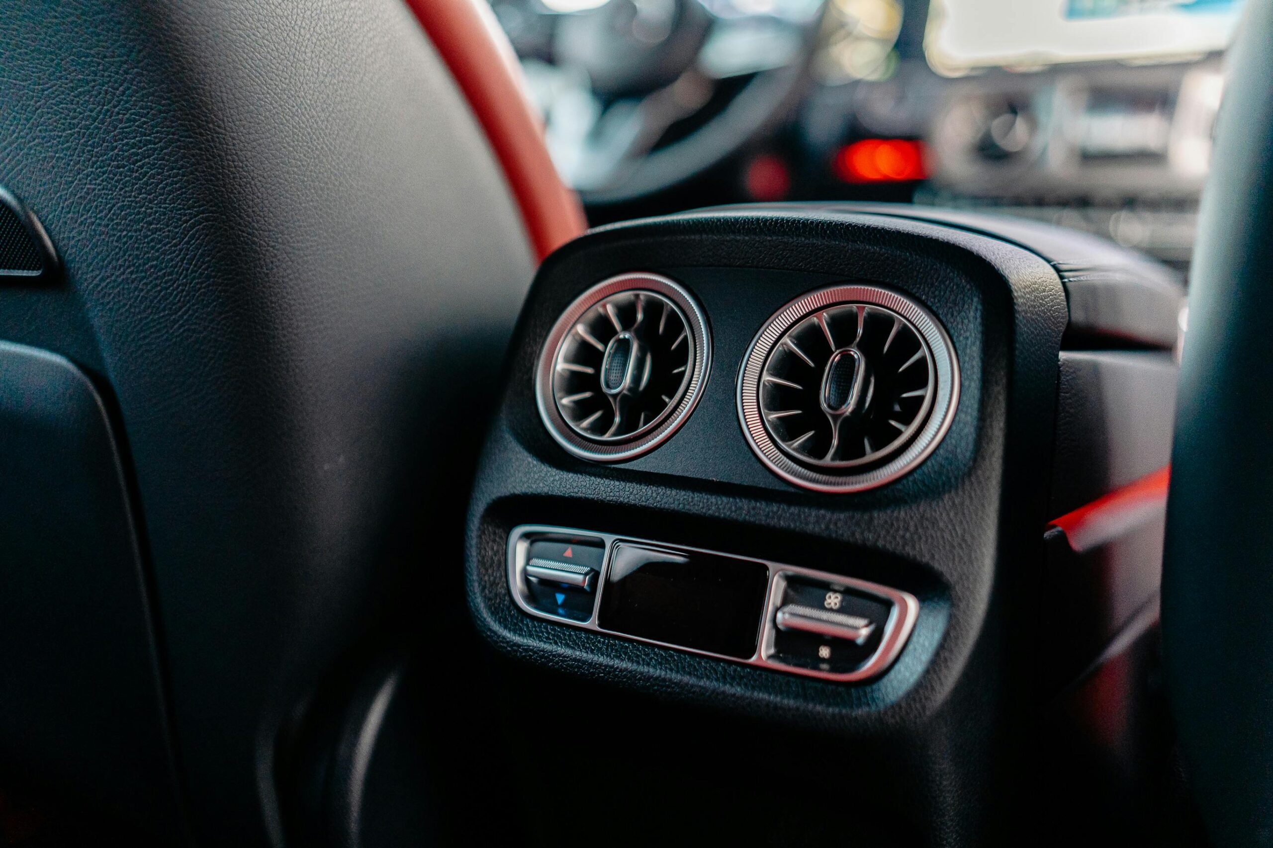 Close-up of car A/C vents showing airflow controls and vents.