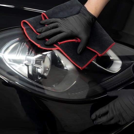 Car headlight cleaning with microfiber cloth for vehicle detailing.