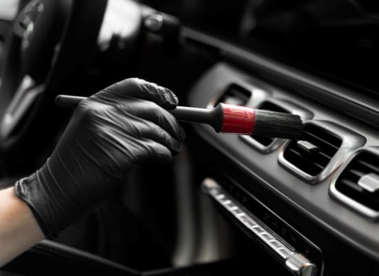 Interior cleaning and detailing of a vehicle dashboard and vents.