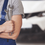 Auto repair technician holding a wrench in a car service shop.