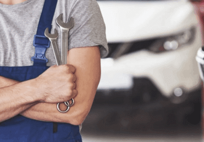 Auto repair technician holding a wrench in a car service shop.