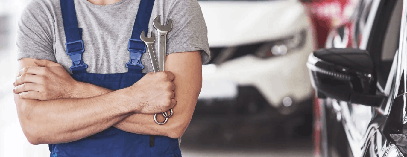 Auto repair technician holding a wrench in a car service shop.
