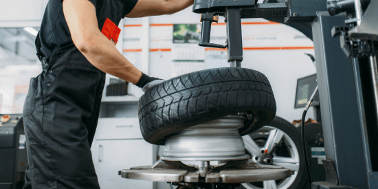 Technician inspecting a car tire at Macy's Tire & Lube service center.