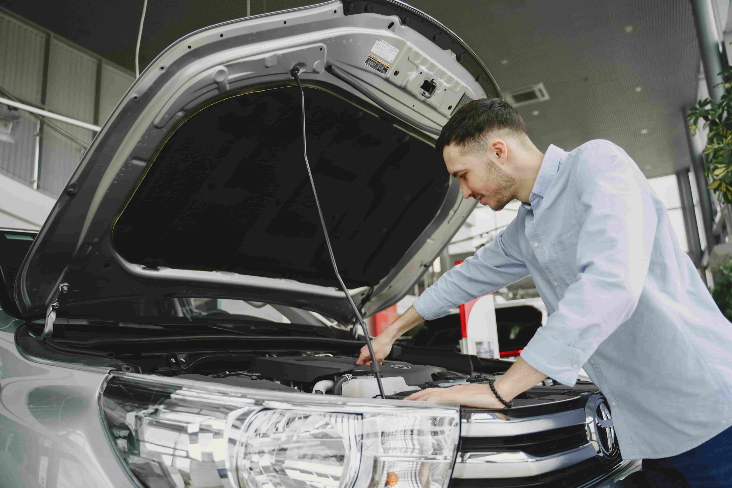 Automotive technician inspecting engine during oil change service at Macy's Tire & Lube.