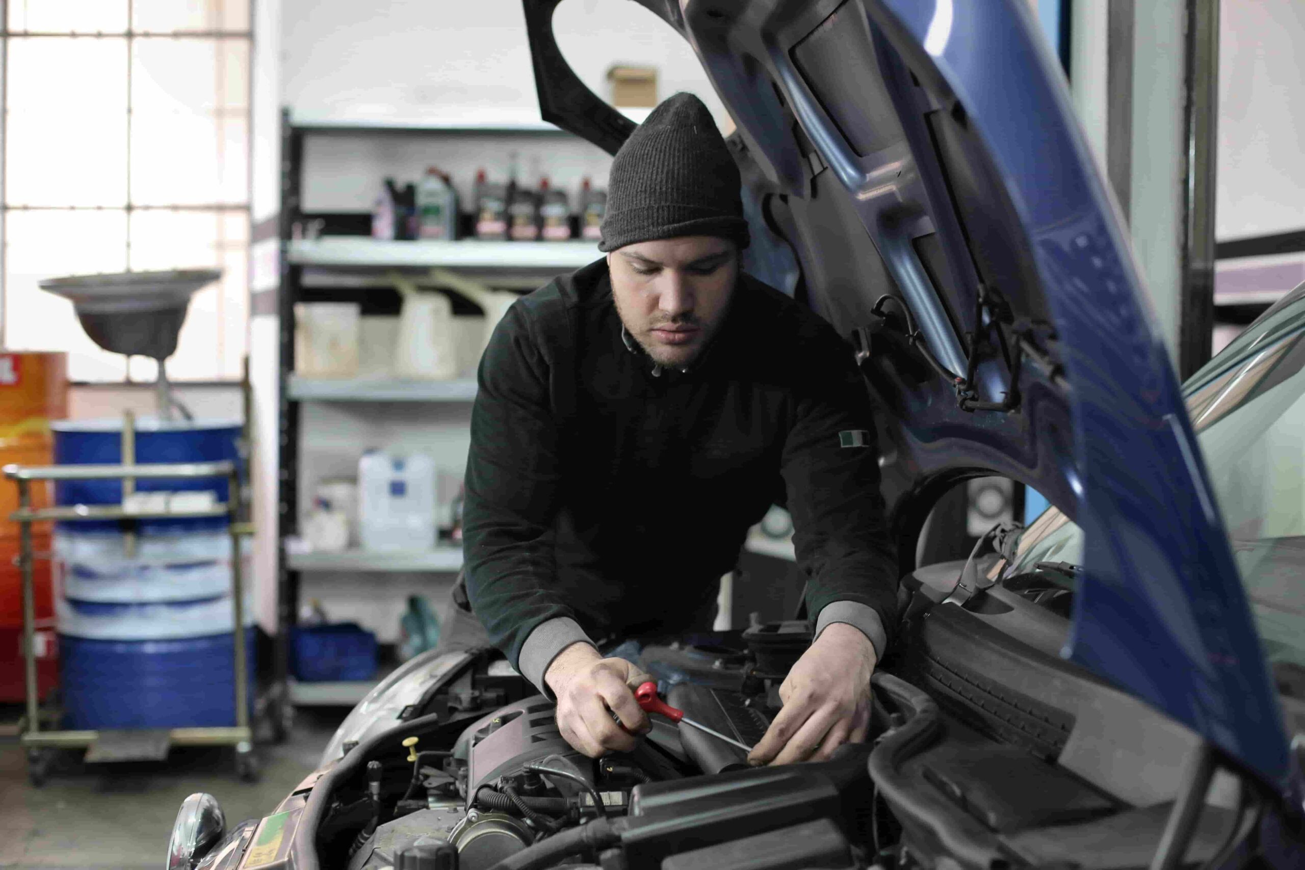 Engine technician performing vehicle inspection and oil check.