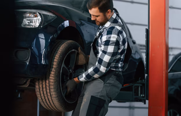 holding-changing-new-tire-man-uniform-is-working-auto-salon