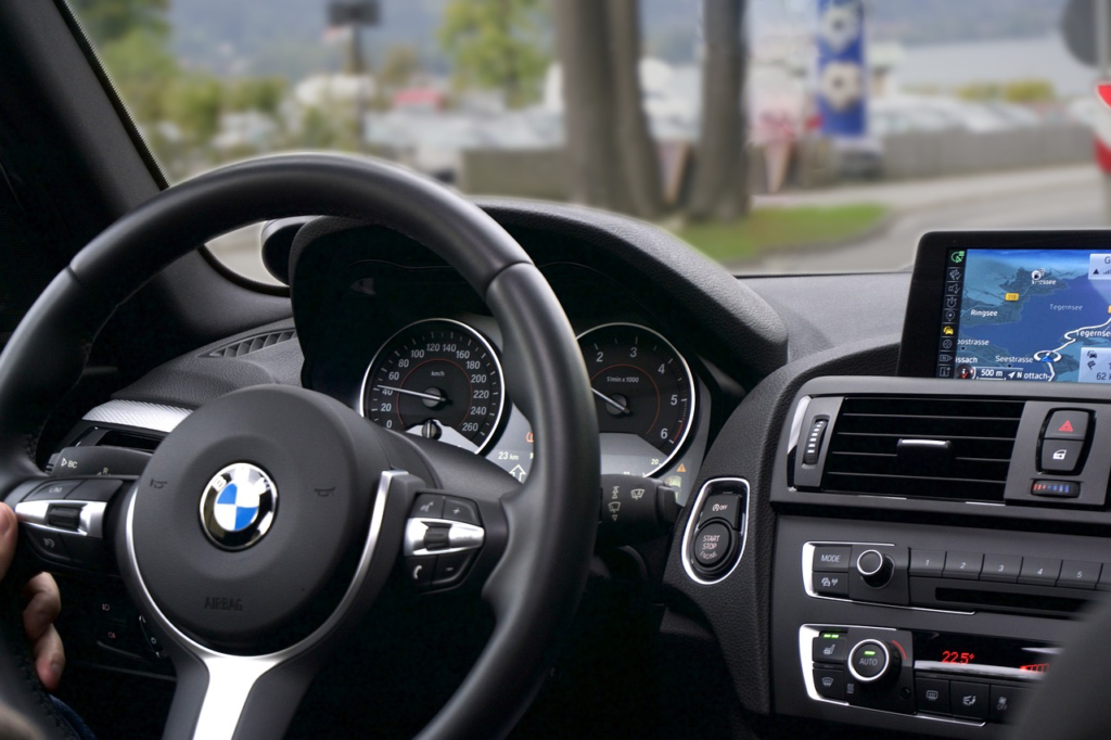 BMW steering wheel and dashboard with navigation system inside a vehicle.