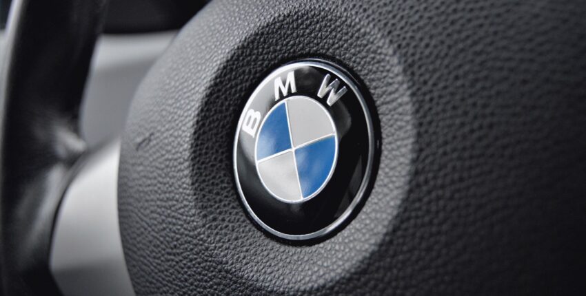 Close-up of BMW emblem on car steering wheel for auto branding.