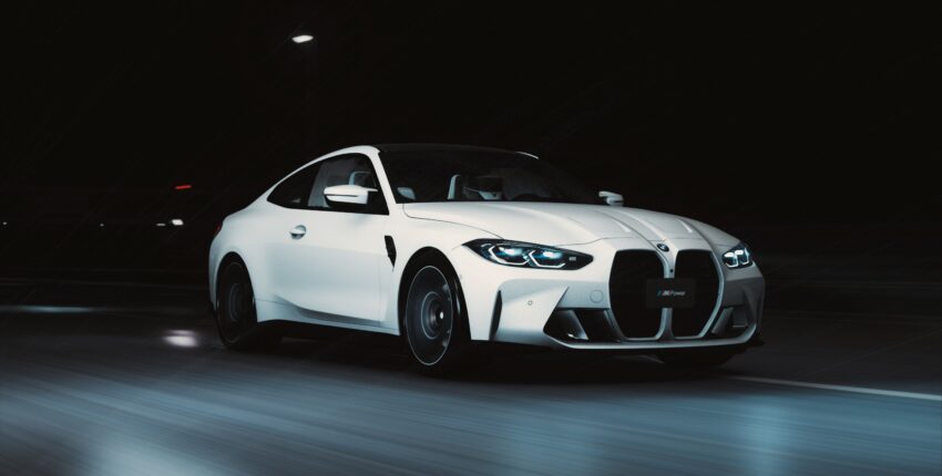 White BMW M4 driving at night with headlights on.