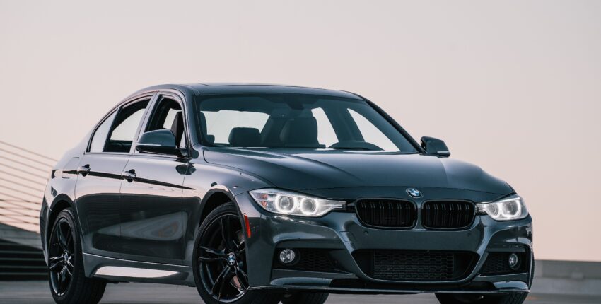 Black BMW sedan parked on road with a clear sky background.