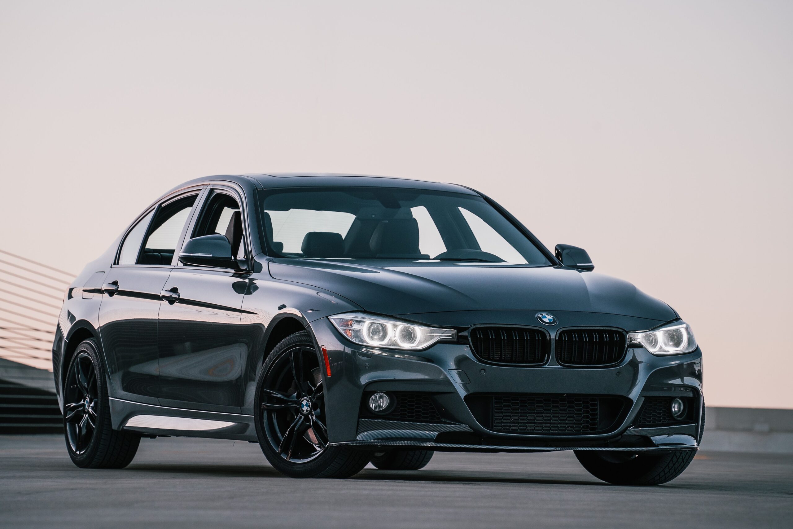 Black BMW sedan parked on road with a clear sky background.