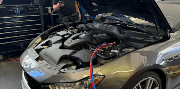 Technician inspecting car's air conditioning system during repair.